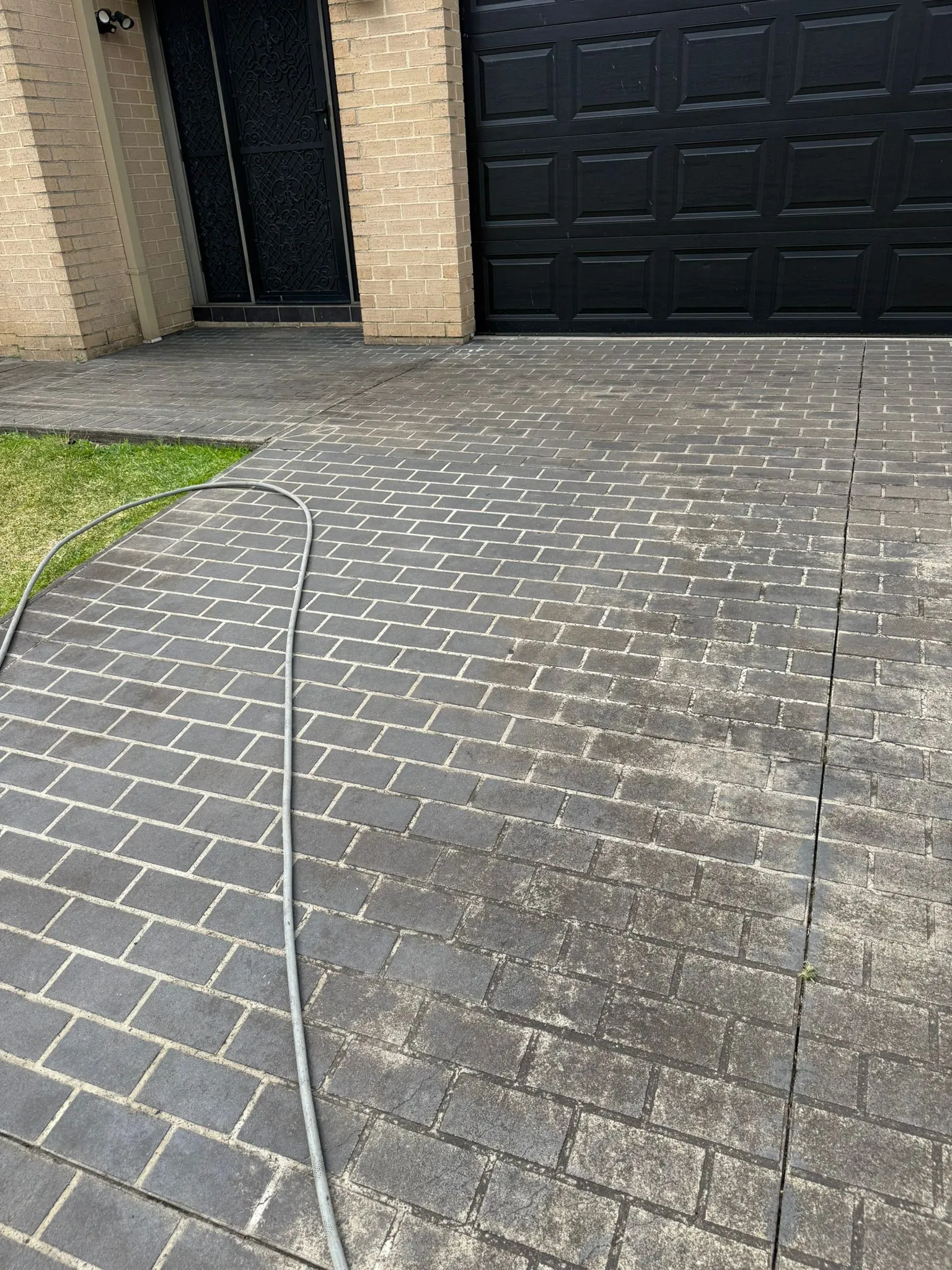 JetBlast Pressure Washing Wotk completion-Paved driveway with a garden hose on a brick surface.